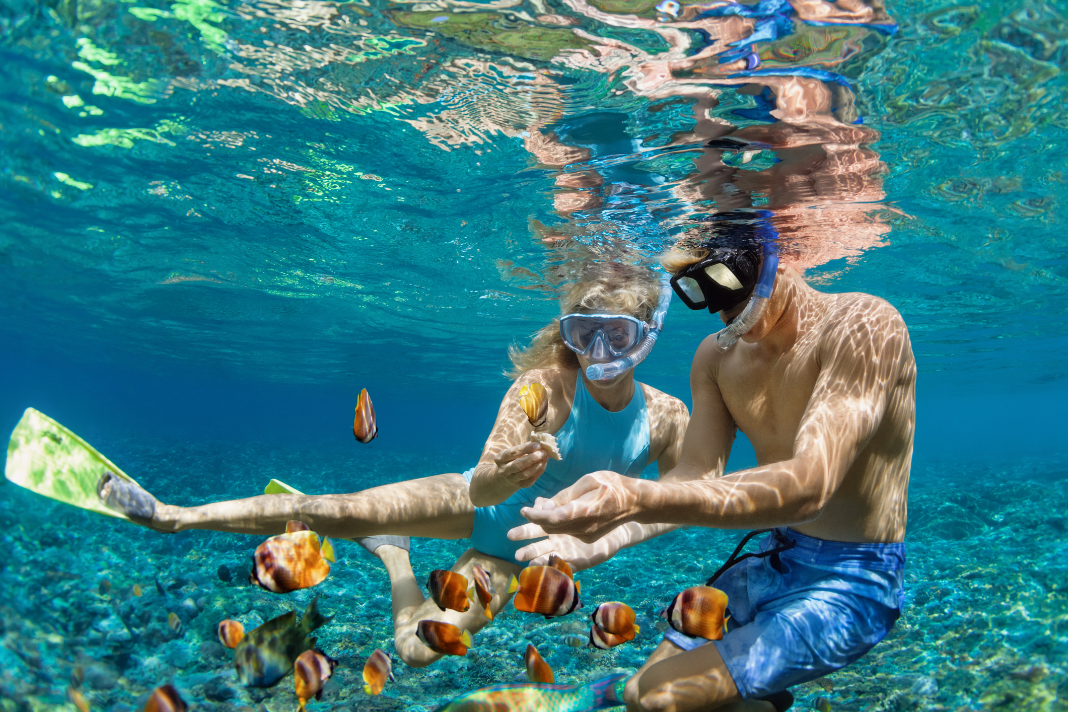 Young couple in snorkeling mask dive underwater in tropical sea Young couple in snorkeling mask hold hand, dive underwater with fishes in coral reef sea pool.