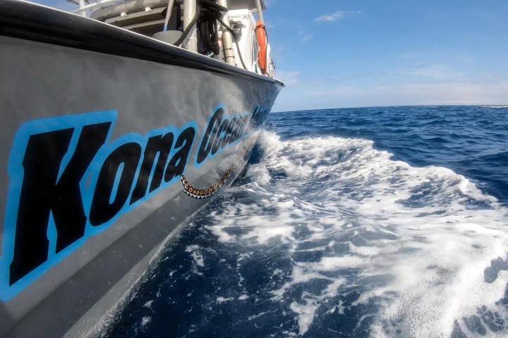 Boat with 'Kona Ocean' on side cruising through blue ocean waves.