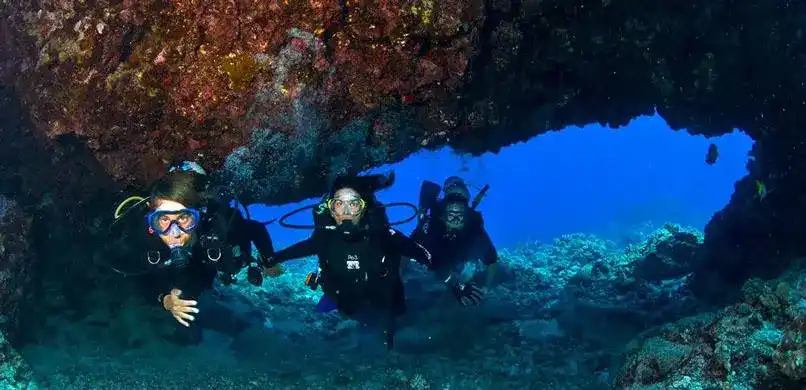 Three divers exploring an underwater cave.