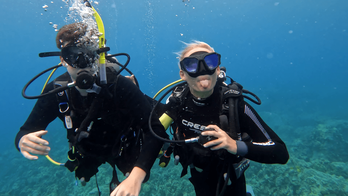 Two young scuba divers float under the water, making funny faces at the camera in Kona, HI