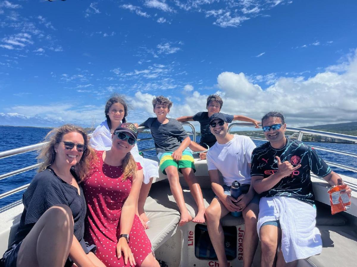Large group enjoys a family-friendly charter boat ride through the waters of Kona, Hawaii. They smile for the camera.